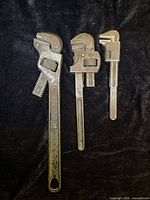 Front view of three steel monkey wrenches showing relative sizes and overall condition