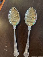 Pair of matching silverplate serving spoons on tabletop, full view