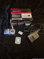 Full lot showing camera, charger, battery, SD card, power cord and box