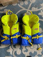 Front view of both Coleman life jackets showing color, belts, and logos