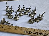 Group of 16 metal knobs arranged beside ruler for scale