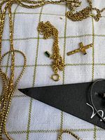 Gold-tone chains, green charm, cross pendant visible