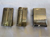 All three lighters side by side showing front designs and wear