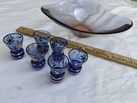Shot glasses arranged beside candy dish with ruler for scale