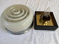 Round glass ceiling fixture beside square candelabra sconce