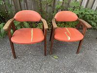 Front view of both armchairs showing torn orange upholstery and wood frames