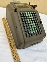 Oblique view of entire adding machine with ruler for scale