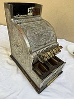 Front three-quarter view showing ornate metal housing, key array, open coin compartments