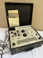 Overall view of Jackson tube tester opened in case with paperwork and power cord