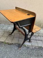 Three-quarter view of vintage desk showing wood top, cast iron frame and bench seat
