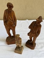 Front view of three wood sailor figurines