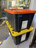 Two stacked HDX totes showing orange and yellow lids