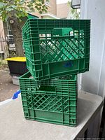 Two green milk crates stacked on a table outdoors