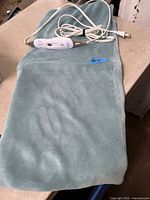 Full view of teal heating pad with controller and cord