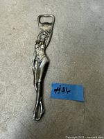 Front view of metal bottle opener shaped as nude female figure with Las Vegas marking