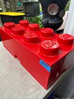 Red LEGO-shaped storage bin exterior showing 8 studs with LEGO logo