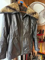 Front view of Danier leather jacket hanging, hood fur visible