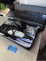 Clipper set inside open Remington case showing clipper, cord, guard attachments, manual