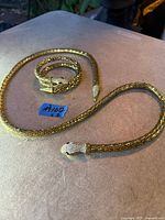 Belt and bracelet coiled on table showing full length and heads