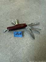 Pocket knife with tools partially opened, showing emblem