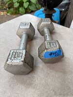 Both 10-lb cast-iron hex dumbbells on surface showing weight markings and wear