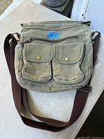 Front view of olive canvas crossbody bag showing pockets, strap and overall condition