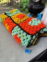 Folded multicolour crocheted blanket on table