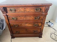 Front view showing marble top, four drawers, brass hardware, carved details