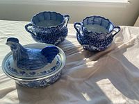 two handled planters and rooster covered dish on tabletop