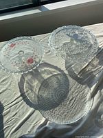 Two pressed glass pedestal cake stands side by side, showing tops and pedestals