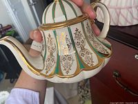 Full view of teapot showing decoration, handle, spout and lid