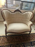 Front view showing ivory tufted upholstery and carved wood frame