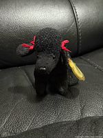 Front view of black poodle plush showing red bows and texture