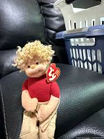 Front view of Ragged Rusty doll seated on leather surface showing outfit and swing tag