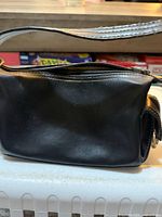 Front view of small black purse showing body and strap