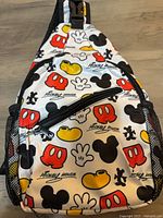 Front view showing Mickey Mouse patterned exterior, front zip pocket, side mesh pocket