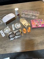 All items laid out: lamp, monomer, tips, powders, wheels, forms, clips, tape