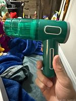 Handheld green vacuum cleaner held in hand