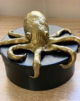 Top view showing gold octopus on black round box