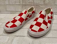 Pair of Vans red and white checkerboard slip-on shoes angled front view