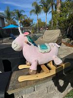 Left side view of pink plush unicorn rocker on wooden base