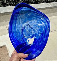 Top view of asymmetrical blue glass bowl showing swirl and pontil