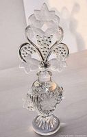 Full view of clear and frosted Art Deco grape design perfume bottle on light surface