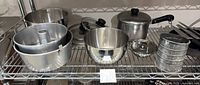 Entire lot on wire shelf including cake pans, mixing bowl, pot, steamer, pan, sifter, knives