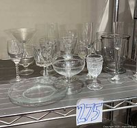 Full group of assorted clear glasses and plates on shelf