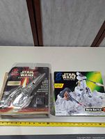 Overview of both sealed Star Wars items with measuring tape for scale