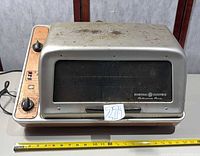 Front view of GE rotisserie oven with measuring tape for scale