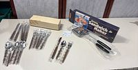 Flatware sets in plastic sleeves, cardboard sleeve, sandwich maker in original box
