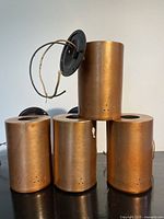 Front and side view of four copper cylinder sconces stacked, showing finish and mounting plates