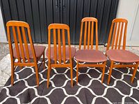 Front view of all four teak chairs on rug